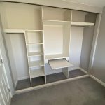 Integrated pull-out desk within a wardrobe interior for compact workspace use.