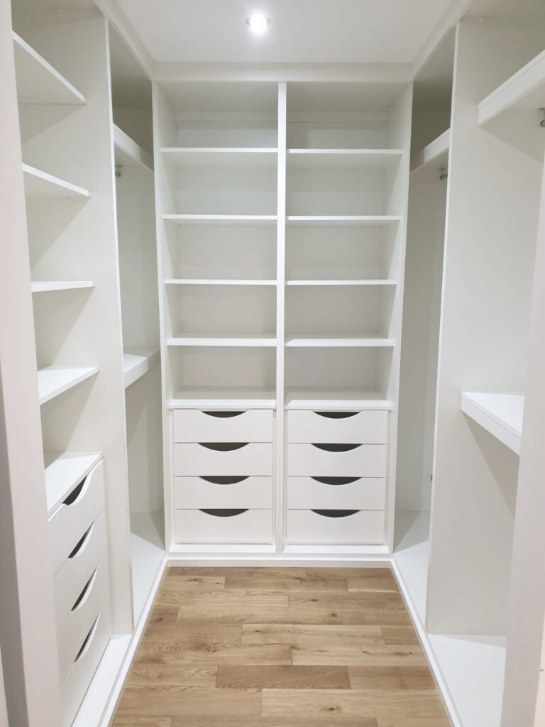 white bespoke walk in wardrobe with custom build drawers, shelving and hanging