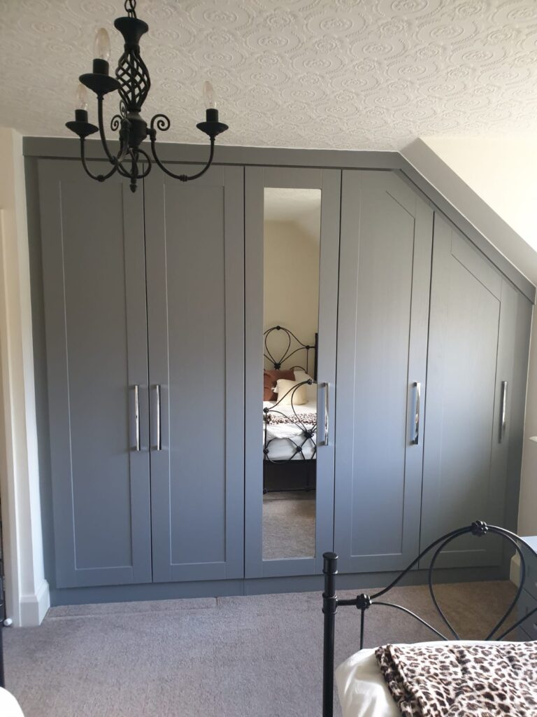 fitted angled wardrobes in the shaker style, dust grey colour. There are five doors, a mirror if fitted to the centre door