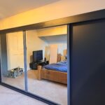 Harrison Monarch sliding door wardrobes in the colour Graphite. Two doors are fitted with Indigo Blue panels, two door are fitted with mirrors.