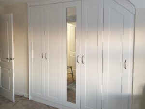 Bespoke fitted shaker style wardrobes with a sloping ceiling, covering a stair bulk head
