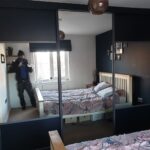 Harrison Monarch sliding door wardorbes in the colour Graphite. Two doors are split with Indigo Blue panels and mirrors.