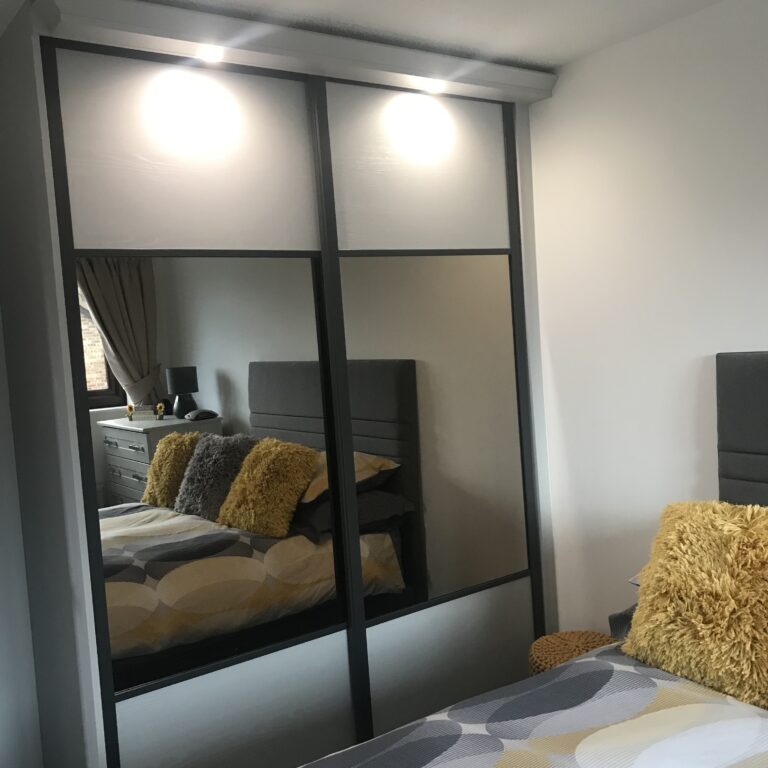 Fitted two door sliding wardrobe with a combination of panels and mirrors. Lights are fitted over the doors