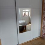 Shaker Slide sliding door wardrobes split with Light Grey panels and a mirror. The carcass ins in contrasting Lissa Oak