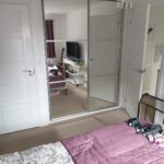Fitted two door sliding wardrobe with silver frames, a white exterior and mirrors fitted into the doors Crittal style.