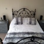 Free standing dust grey shaker style bedside tables either side of a framed bed