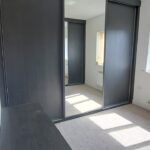 Fitted three door sliding wardrobe in the colour Graphite. The two outer doors are fitted with Graphite panels, the centre door is fitted with a mirror.