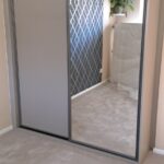 Fitted two door sliding wardrobe. One door is fitted with a Dust Grey panel, the other is fitted with a mirror.