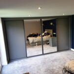 Fitted four door sliding wardrobe in the colour Graphite. The two outer doors are fitted with Graphite panels, the two centre doors are fitted with mirrors.