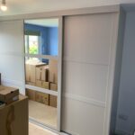 Fitted shaker style sliding door wardrobe. The two outer doors are fitted with Cashmere coloured panels. The centre door is fitted with a mirror.