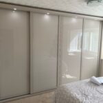 Fitted sliding door wardrobes in the colour Cashmere. There are four doors in the wardrobe and each door is fitted with Cashmere coloured glass.