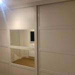 Fitted sliding door wardrobes in the colour Cashmere. The two outer doors are fitted with Cashmere Shaker style panels. The centre door is fitted with Cashmere panels at the top and bottom and two mirrored sections in the centre.