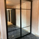Fitted two door sliding wardrobe with black frames and mirrors fitted.