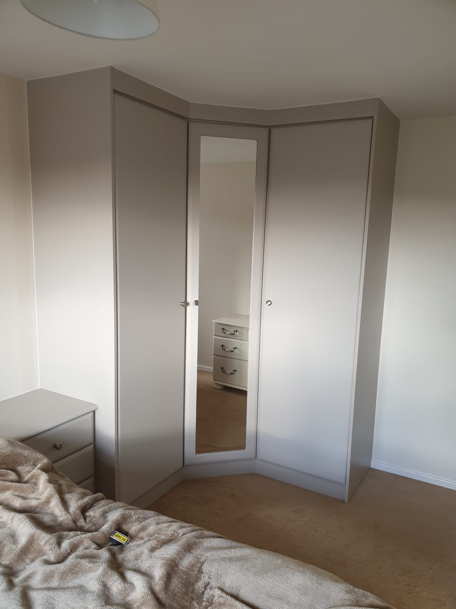Corner wardrobe with white doors, silver handles, and mirror