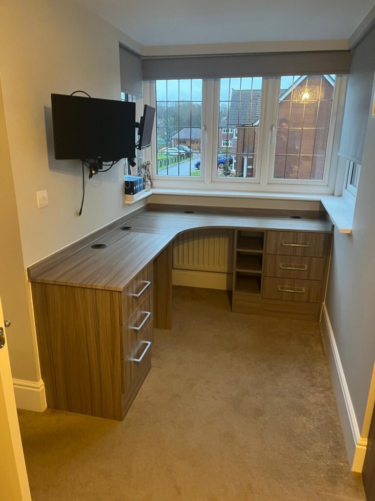 Bespoke fitted home office furniture in a brown wood colour finish. There are two chests of three drawers, a small cubed shelving area, a curved corner desk and a straight desk