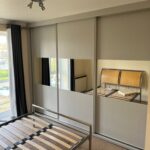 Bespoke fitted sliding door wardrobes. Three doors. Each door is split into three with Light Grey panels and mirror in the centre