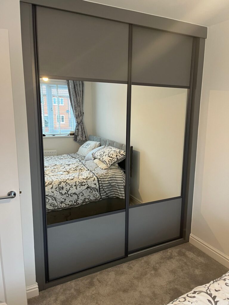 Bespoke fitted sliding door wardrobes in the colour Graphite. Both doors are split with Graphite panels at the top and bottom and a large mirror in the centre