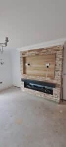 Media wall build with red bricks. An integrated fire is fitted with a Halifac Oak matelpiece,. A recess is included with a Halifax Oak back board and trim for the TV to fit into. Halifax Oak shelving is fitted either side of the brickwork, floor to ceiling.