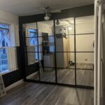 Bespoke fitted sliding door wardrobes in the colour black. There are four doors, each door is in the crittal style.