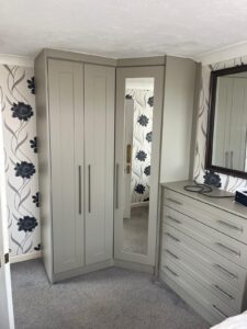 Fitted hinged door wardrobe with miroored corner wardrobe, double wardrobe and tall boy drawers.