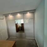 bespoke fitted sliding door wardrobe with lighting, mirrors, panels and coloured glass.