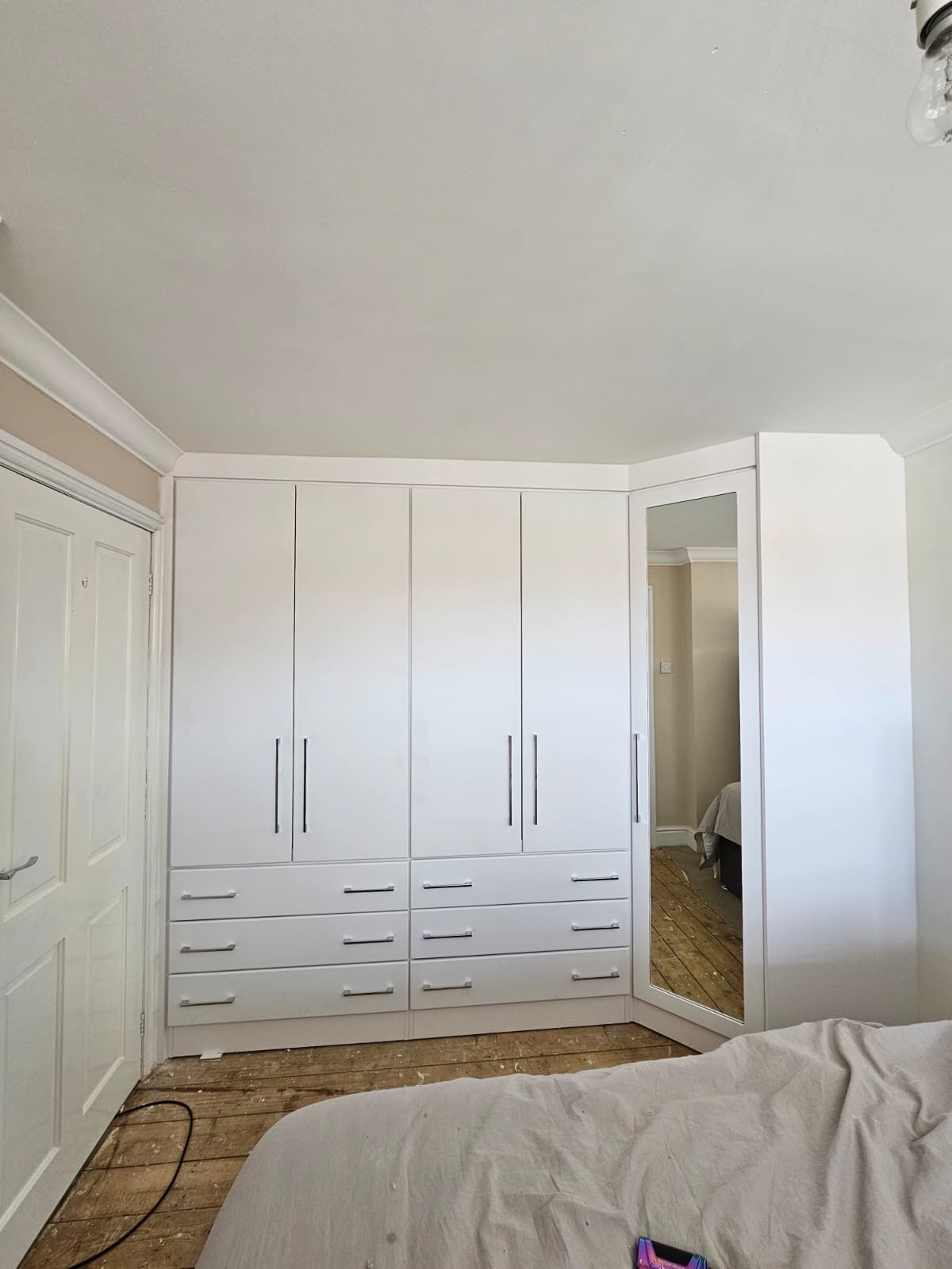 Manhattan style doors and drawers fitted around a corner. Bridge Over Bed.