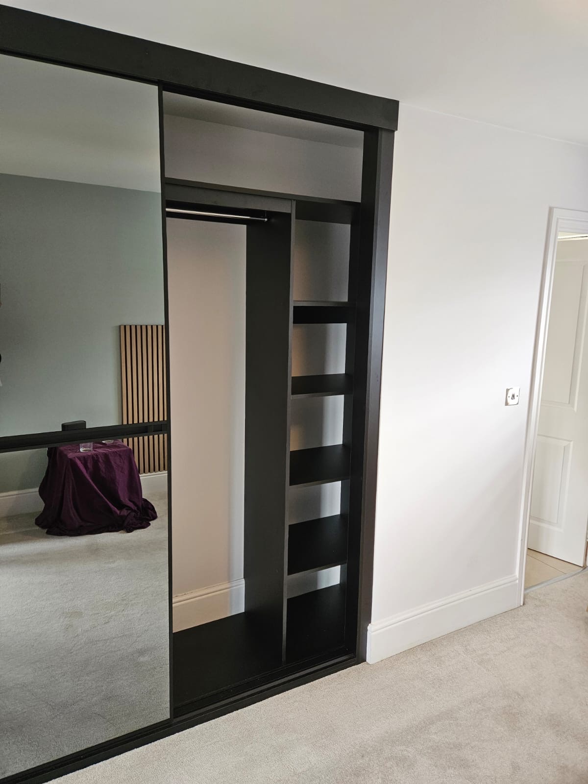 Sliding mirrored wardrobe interior with hanging rails and shelves