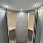 interior of white corner wardrobe with shelves, rails, and interior lighting