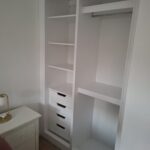 White built into wall closet with rail, shelves and 4 drawers