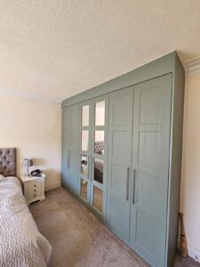 Green Grained bespoke shaker panelled wardrobes with mirrored wardrobe doors and solid wardrobe doors by Creative Joinery