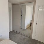 Bespoke alcove wardrobe with one mirrored sliding door and one panelled sliding door in the colour Cashmere