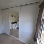 Mirrored sliding door Shaker panel wardrobe in white.