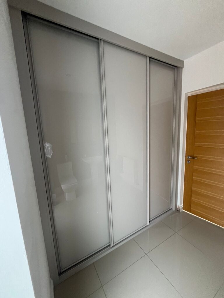 Fitted sliding door wardrobe with three doors. The doors have a Cashmere coloured frame and are all fitted with Cashmere coloured glass.