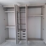 Fitted wardrobe interior with hanging space, shelving, drawers and a mirror.