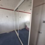 Fitted sliding door wardrobe with two mirrored sliding doors in the colour white.