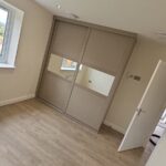 Made to measure Shaker Stone Grey sliding door wardrobe with two doors. The doors have a horizontal split in the centre with a narrow mirror.