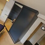 Bespoke Navy sliding door wardrobes scribed around a beam at the back of the wardrobe. There are two sliding doors. One is fitted with a floor to ceiling mirror, the other a solid Indigo Blue (Navy) panel.