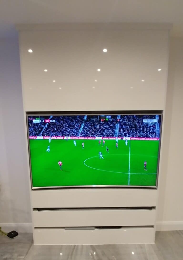 TV mounted into High Gloss White wall panel with drawers below.