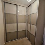 Made to measure corner sliding wardrobes with two tone finish of Cashmere coloured glass and Stone Grey coloured glass