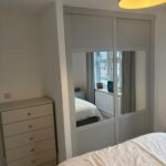 bespoke fitted furniture in the colour Light Grey. Custom alcove wardrobes are fitted with Shazker sliding doors in the colour Light Grey with a combination of mirrors and panels. There are free standing tall boy drawers to match the wardrobes