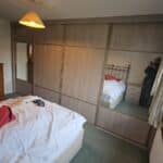 Made-to-measure sliding door wardrobes with grey tone wood grain panels and mirrored doors