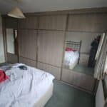 Made-to-measure sliding door wardrobes with grey tone wood grain panels and mirrored doors