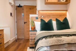 custom furniture in a wood grain finish combined with a dark grey finish. Creative Joinery fitted a custom headboard with a shelf, bespoke drawers and fitted over bed shelving.