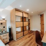 custom sliding door wardrobe with wood grain and mirrored doors. Accompanied by a matching custom bedside drawers in two tone wood grain and dark grey finish.