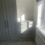 Custom wardrobes and tallboy drawers with Shaker style doors in a neutral light grey finish.