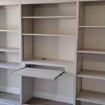Integrated pull-out desk within a wardrobe interior for compact workspace use.