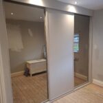 Custom Bronze Tinted Mirrored sliding doors and a Cashmere panelled sliding door as part of a wall to wall wardrobe installation