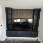 Made-to-measure media wall with Shaker low-unit cupboards, bookcase shelving and acoustic wall panelling. Finished in a combination of Walnut and Navy Blue.
