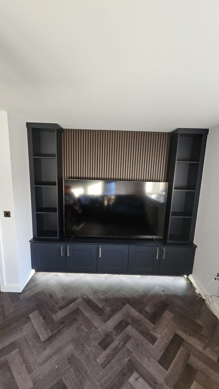 Made-to-measure media wall with Shaker low-unit cupboards, bookcase shelving and acoustic wall panelling. Finished in a combination of Walnut and Navy Blue.
