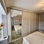 Custom Shaker sliding door wardrobe in neutral colour finish by Creative Joinery Chorley.